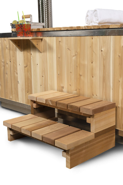Two tier cedar step and the drink shelf above it, both optional accessories, against the vertical cedar skirt of the Starlight hot tub.